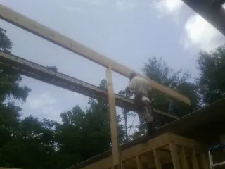 Carpenter setting a ridge beam over a new addition frame — Ice Dam Removal by Roofing Brothers in Arlington